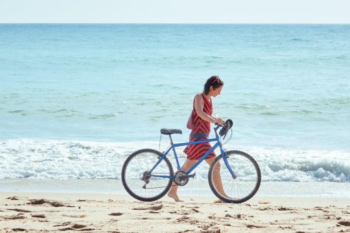 a woman bringing her bicycle next to a body of water