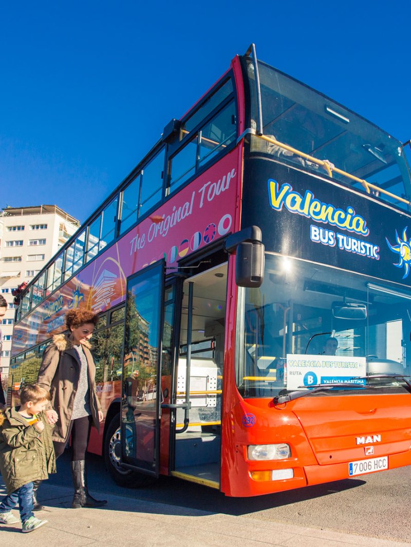 3 people walking near a bus