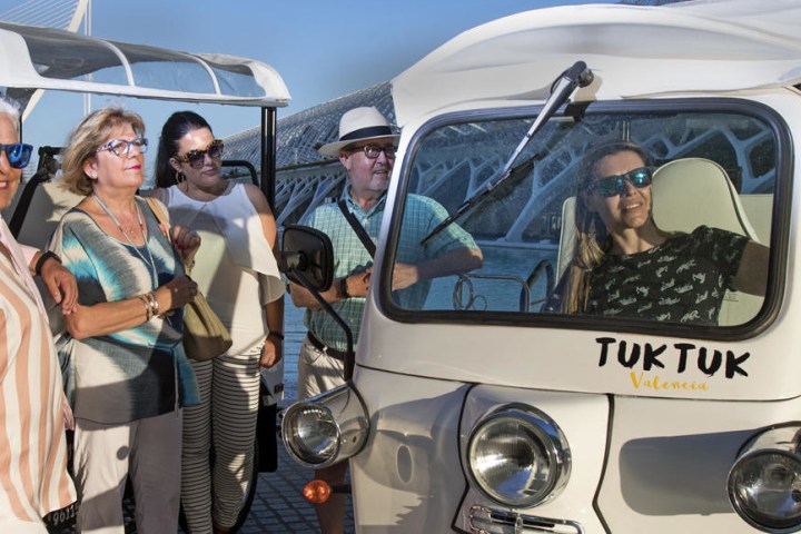 a group of people standing in front of a tuk tuk