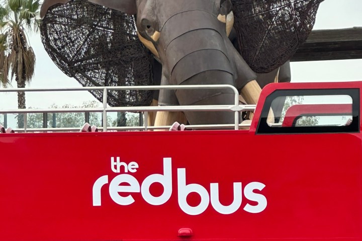Red double-decker bus with large elephant sculpture on top.